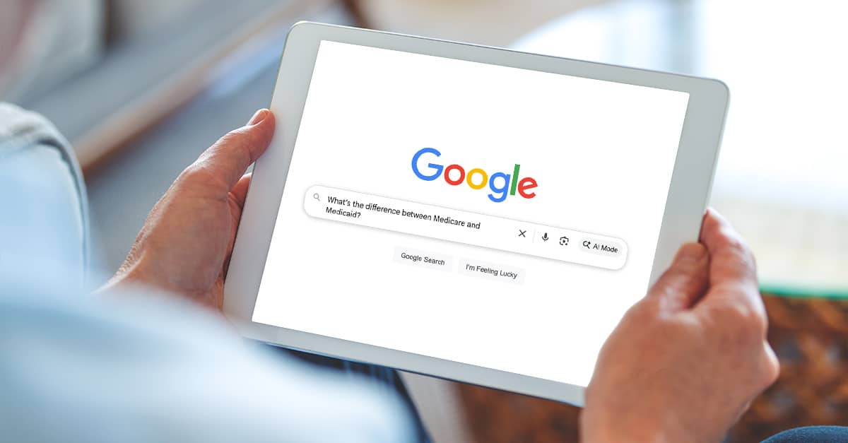 Mature man using a digital tablet at home while sitting on the sofa with a Google Search on the screen for "What is the difference between Medicare and Medicaid?"