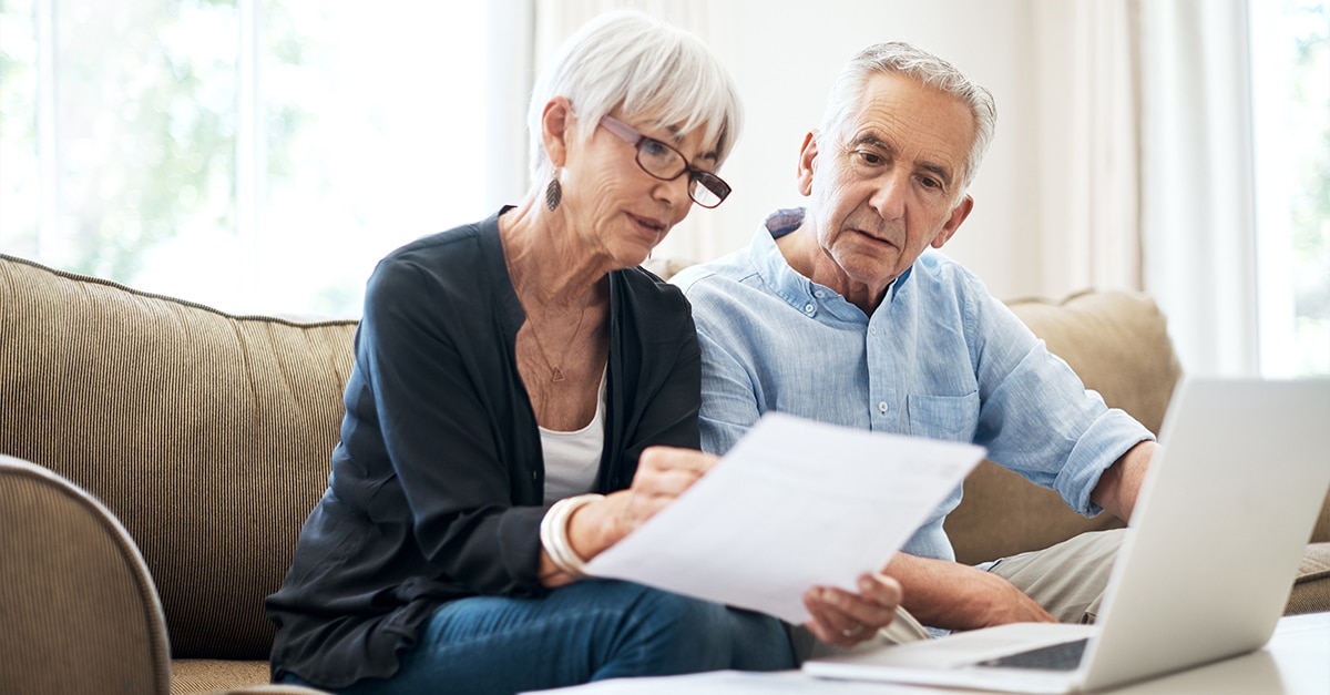 Senior couple reviewing Medicare Advantage paperwork while sitting on a couch at home.